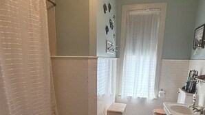 A bathroom with a shower, toilet, sink, and a rug on the floor.