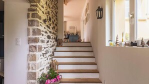 Eine Treppe mit Steinwänden, ein Fenster mit Dekoration und eine Tür mit Lichtschalter.
