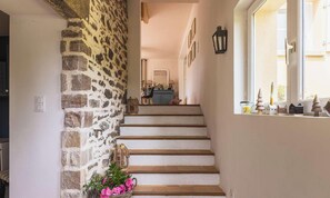 A staircase with stone walls, a window with decorative items, and a door with a light switch. - Authentic Breton farmhouse | 8 guests | Ref 307 (PLEBOULLE)