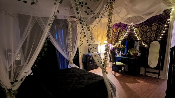 A bedroom with a bed, a vanity with a mirror, and a desk with a chair. - Victorian Fairy Cottage (Houston)