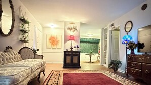 A living room with a sofa, a red rug, a lamp, and a mirror on the wall. - Victorian Fairy Cottage (Houston)