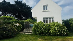 Ein weißes Haus mit Satteldach, einem kleinen Fenster und einem Schornstein.