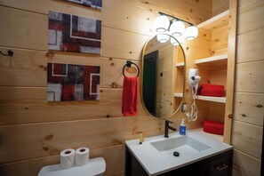 A wooden cabin bathroom with a sink, mirror, towel rack, and toilet paper. - Terrace Creek Retreat | Creekside Hot Tub Escape | 5 Min From Nada Tunnel! (Stanton)