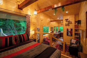 Ein Holzblockhaus-Interieur mit Bett, Schreibtisch und Blick auf den Wald.