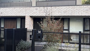 Een modern gebouw met een bakstenen gevel, grote ramen en een zwart metalen hek.