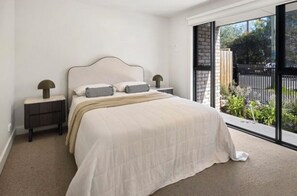A bedroom with a large bed, two bedside tables, and a window with a view of the outside. - Urban Delight (Burnley)