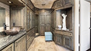 A spacious bathroom with wooden cabinetry, a granite countertop, and a marble floor. - Lakefront Oasis | Infinity Edge Pool & Golf Views (Glendale)