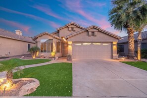 A residential house with a garage, a well-maintained lawn, and a palm tree. - Lakefront Oasis | Infinity Edge Pool & Golf Views (Glendale)