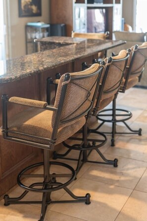 A bar area with a long counter and four bar stools. - Lakefront Oasis | Infinity Edge Pool & Golf Views (Glendale)