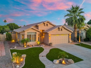 A two-story house with a garage, a well-maintained lawn, and a palm tree. - Lakefront Oasis | Infinity Edge Pool & Golf Views (Glendale)