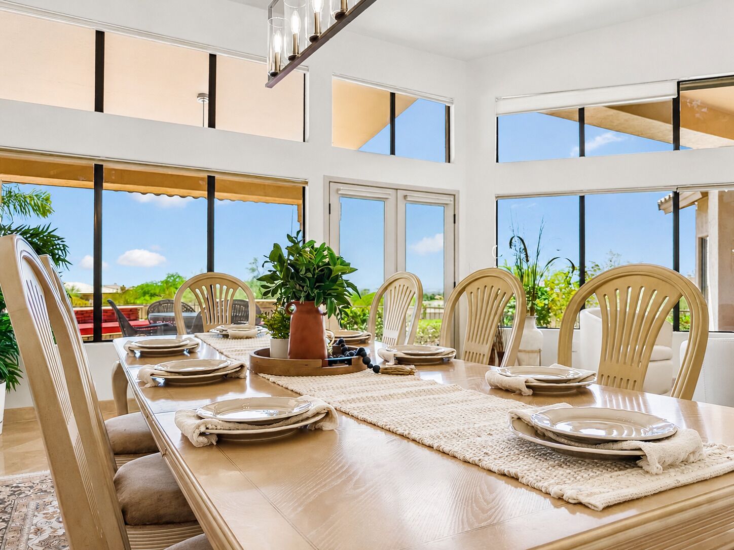 A dining area with a long table, chairs, and a potted plant.