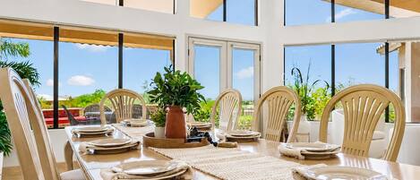 A dining area with a long table, chairs, and a potted plant.