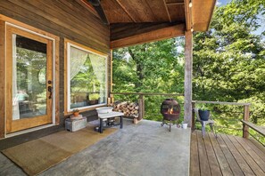 A covered porch with a grill, a table with chairs, and a view of the surrounding forest. - Amazing views 15 minutes from Fayetteville square! (fayetteville)