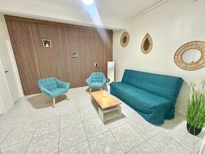 Ein Wohnzimmer mit einer Couch, zwei Sesseln, einem Couchtisch und einem dekorativen Spiegel.