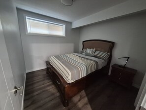 Une chambre à coucher avec un lit, une table de chevet, une fenêtre et une porte.