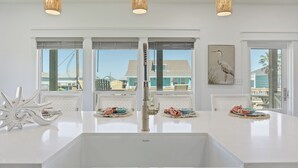 Una cocina con cubierta blanca, un lavamanos y tres lámparas colgantes.