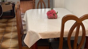 A dining area with a table set for four, wooden chairs, a potted plant, and a view through an open door. - Cozy Apartment in the Historic Center of Porto Alegre (Porto Alegre)