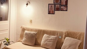A living room with a sofa, a wall-mounted light, and framed pictures. - Cozy Apartment in the Historic Center of Porto Alegre (Porto Alegre)