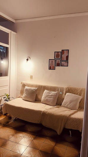 A living room with a sofa, a wall-mounted light, and framed pictures. - Cozy Apartment in the Historic Center of Porto Alegre (Porto Alegre)