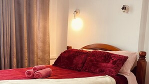 A bed with red bedding, a wooden headboard, and a white wall with a light fixture. - Cozy Apartment in the Historic Center of Porto Alegre (Porto Alegre)