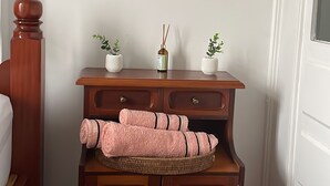 A wooden cabinet with two drawers and a shelf, a small potted plant, and a rolled-up pink towel on the shelf. - Cozy Apartment in the Historic Center of Porto Alegre (Porto Alegre)