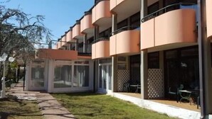 A multi-story hotel with balconies, large windows, and a well-maintained lawn. - Royal Suite (Garda)