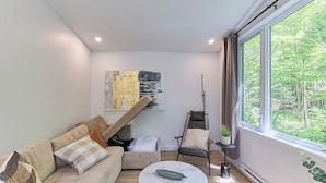 A modern living room with a sofa, a chair, a coffee table, and a painting on the wall. - Astral - Private Hot Tub, Pet-Friendly (Pont-Rouge)
