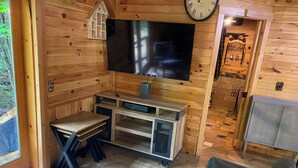 A wooden cabin interior with a TV, a small table, a couch, and a clock on the wall. - Rustic Cabin, feeling like a home ! (Mariaville)