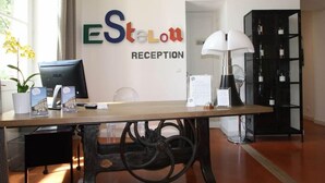 A reception desk with a computer, brochures, and a lamp. - Hotel De L'estelou (Sommieres)