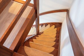 Eine hölzerne Treppe mit geschwungenem Geländer und einer weißen Wand.