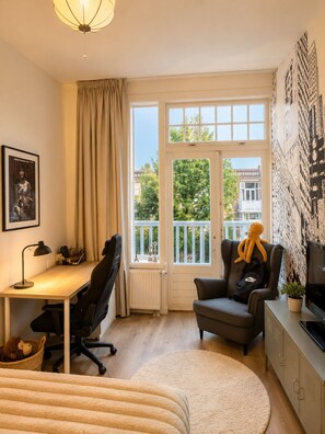 Ein modernes Zimmer mit Schreibtisch, Stuhl und einem großen Fenster mit Blick auf Gebäude.