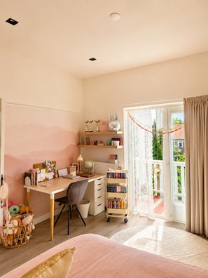 Ein Schlafzimmer mit Schreibtisch, Bücherregalen, einem Bett und Blick ins Freie.