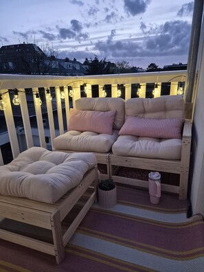 En balkong med en bekväm sittplats, ett litet bord och en vattenflaska.