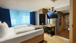Une chambre d’hôtel équipée d’un lit, d’un bureau, d’une chaise, d’une télévision et d’une salle de bain avec douche.