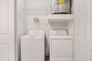 A laundry room with two front-loading washing machines and a stacked dryer. - Frisco Getaway with Pool, Gym & Free Parking (Frisco)