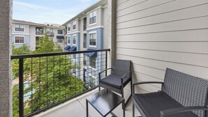 A balcony with a metal railing, a small table, and two chairs. - Frisco Getaway with Pool, Gym & Free Parking (Frisco)