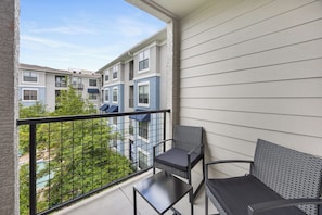 A balcony with a metal railing, a small table, and two chairs. - Frisco Getaway with Pool, Gym & Free Parking (Frisco)