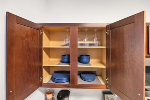 A wooden cabinet with shelves containing blue bowls and wine glasses.
