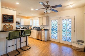 A kitchen with a bar area, a ceiling fan, and a sign on the wall. - Desert Disco Hideaway • Private Pool, Spa, Sleeps 8 • 5 Min to PHX airport (Phoenix)