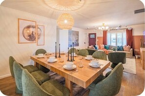 A dining area with a wooden table set for four, green upholstered chairs, a hanging light fixture, and a framed artwork on the wall. - Desert Disco Hideaway • Private Pool, Spa, Sleeps 8 • 5 Min to PHX airport (Phoenix)