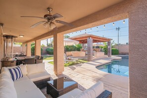 Une terrasse extérieure avec une piscine, un ventilateur de plafond et un coin repas.