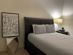 A neatly made bed with a dark headboard, a bedside table with a lamp, and a framed abstract artwork on the wall. - 3 bedrooms & 2 bathrooms condo at Vanderbilt Country Club in Naples, Florida (Naples)