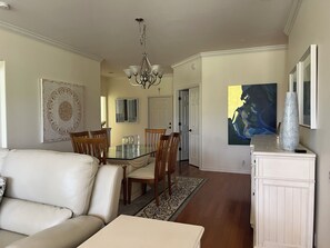 A dining area with a glass table and chairs, a chandelier, a white cabinet, and a large abstract painting. - 3 bedrooms & 2 bathrooms condo at Vanderbilt Country Club in Naples, Florida (Naples)