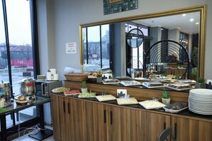 Balcão de buffet com diversos alimentos, um espelho grande e vista para o exterior.