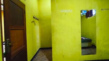 A room with yellow walls, a wooden door, a tiled floor, and a small window.
