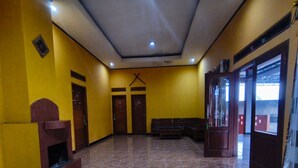 A spacious lobby with a tiled floor, wooden benches, and a large glass door leading outside.