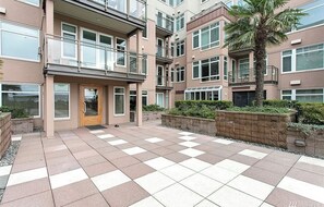A multi-story residential building with a checkered tile courtyard, balconies, and a palm tree.
