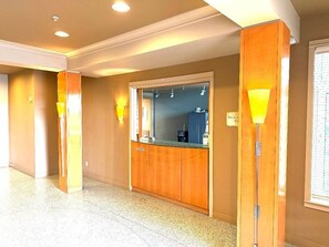 A hotel lobby with a reception desk, wooden paneling, and a large mirror.