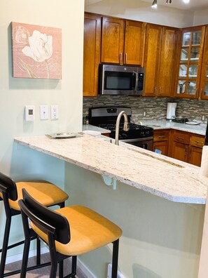 A kitchen with wooden cabinets, a stainless steel microwave, a gas stove, and a marble countertop.