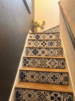 A staircase with patterned tiles and a vase with yellow flowers at the top.